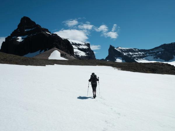 a person is walking through a snowy field with mountains in the background .