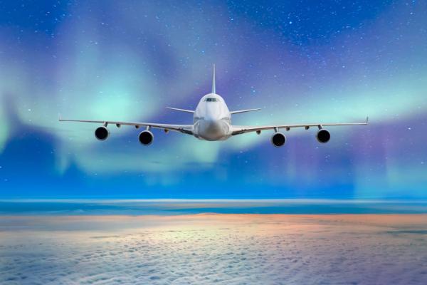 Avión volando bajo la aurora boreal