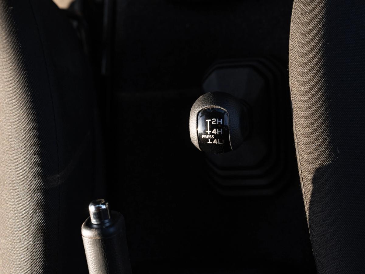 Jimny-Verteilergetriebehebel Manueller Verteilergetriebehebel im Suzuki Jimny mit den Markierungen 2H, 4H und 4L neben der Handbremse