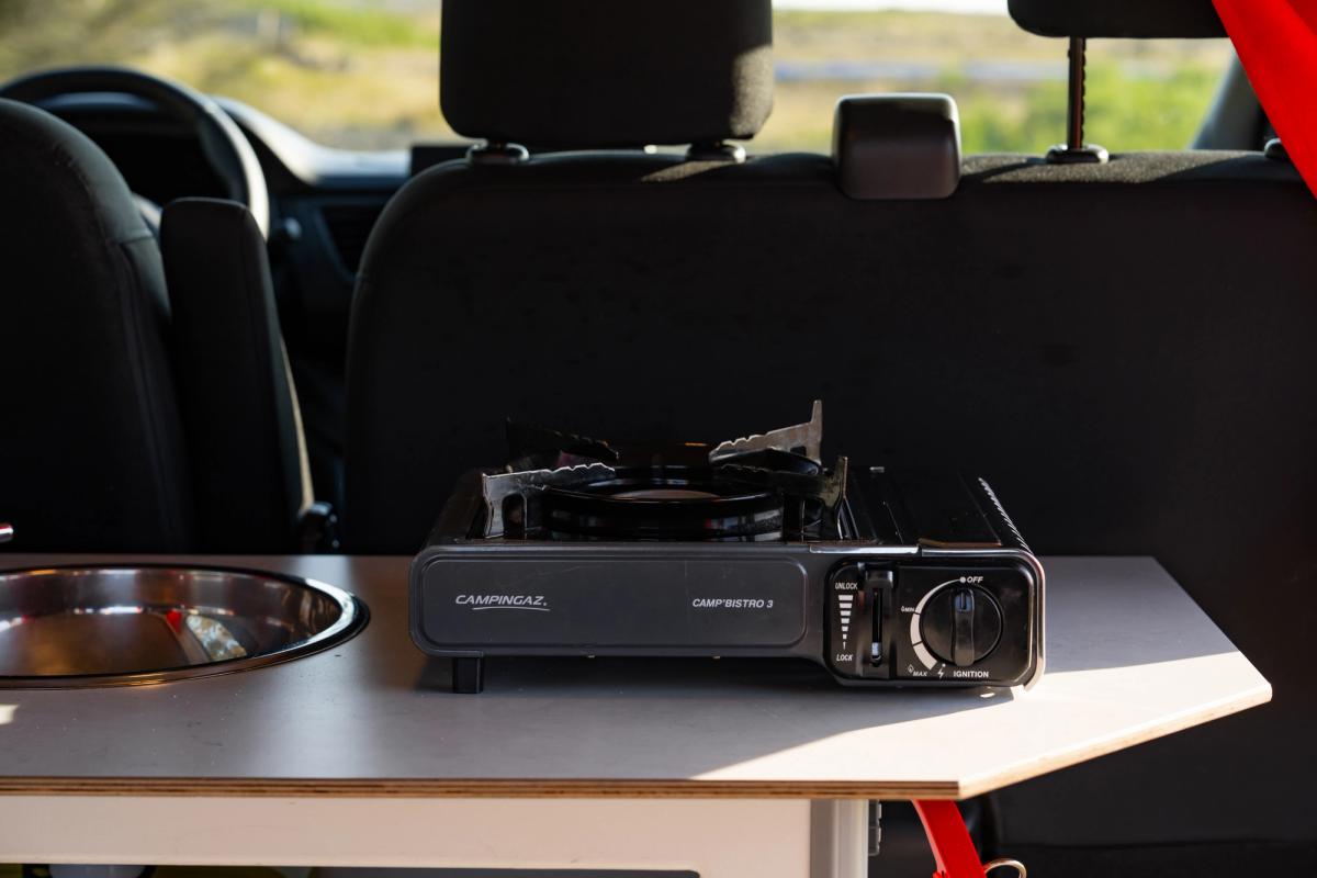 Portable single burner gas stove on the kitchen counter beside the sink
