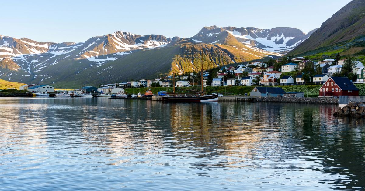 town by the water with fjords and snowy mountains in the background
