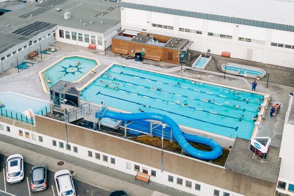 an aerial view of a swimming pool with a water slide in front of a building .