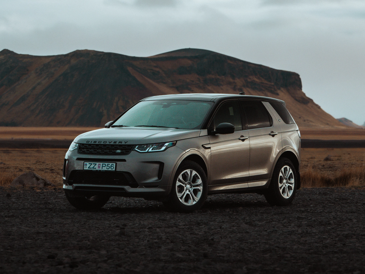 Discovery Sport vor Bergkulisse Land Rover Discovery Sport 4x4 auf einem offenen Feld geparkt, mit Bergen im Hintergrund