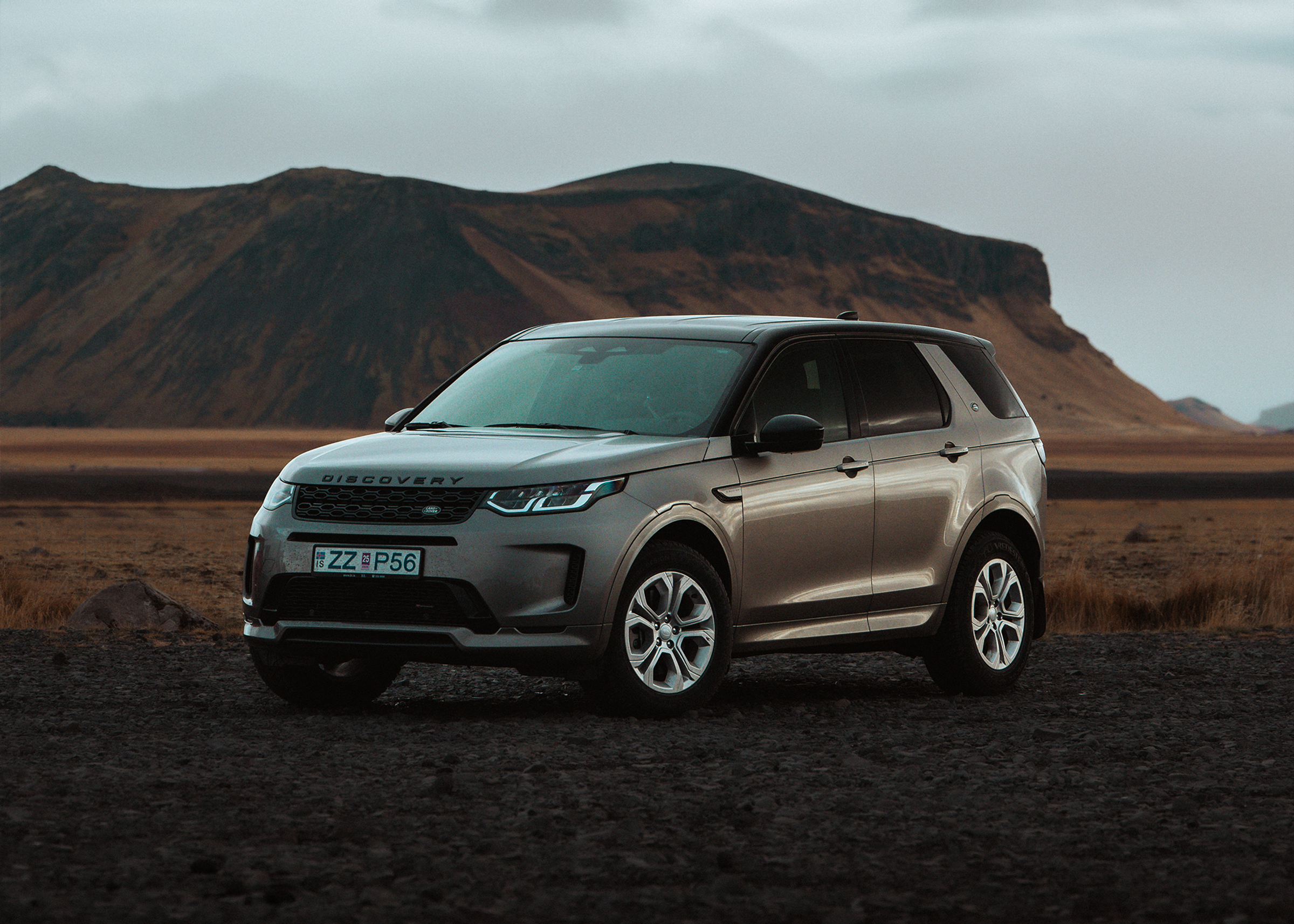 Discovery Sport vor Bergkulisse Land Rover Discovery Sport 4x4 auf einem offenen Feld geparkt, mit Bergen im Hintergrund