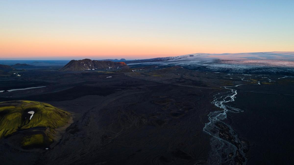 an aerial view of a mountain range with a river running through it at sunset .