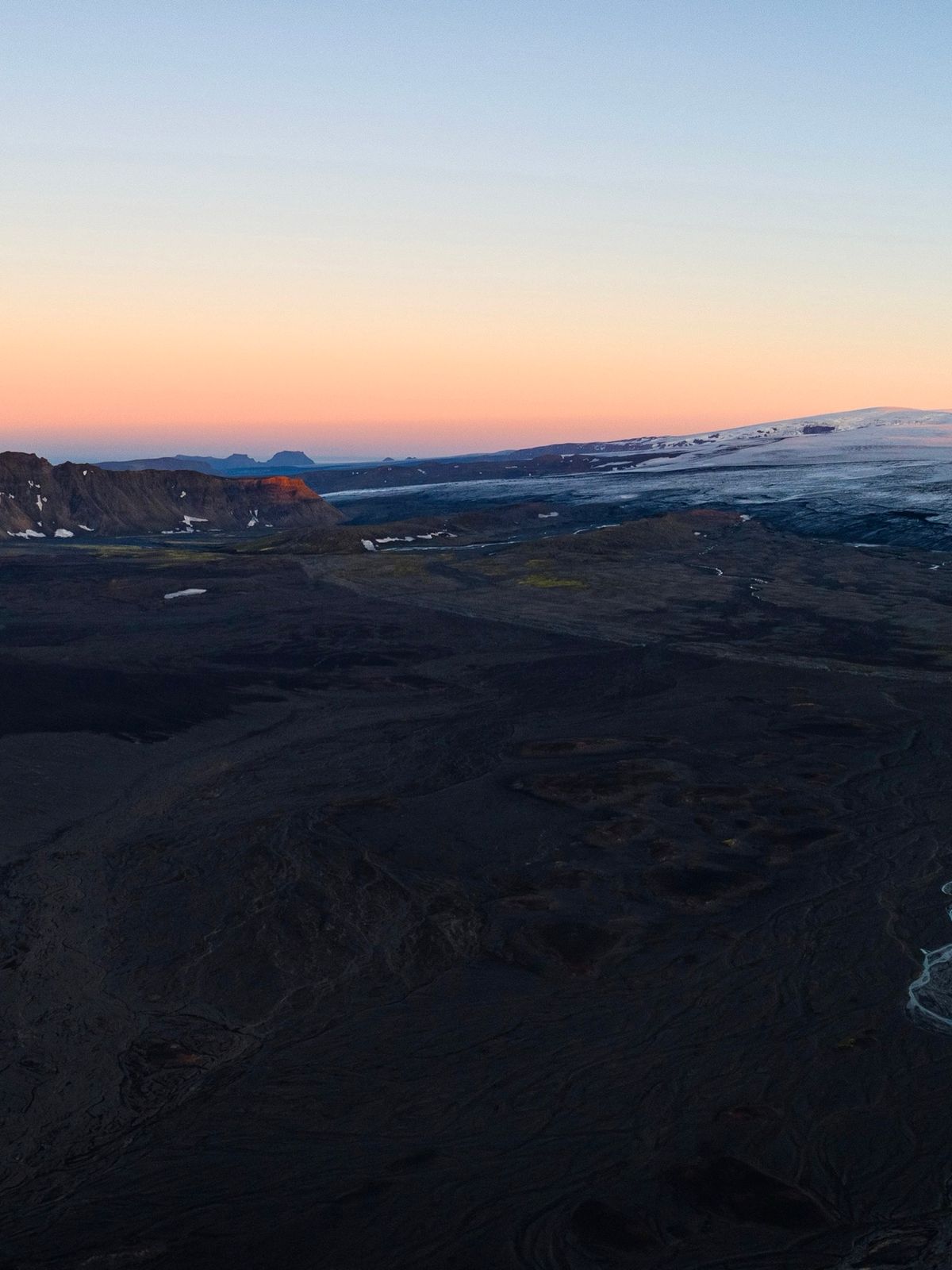 an aerial view of a mountain range with a river running through it at sunset .