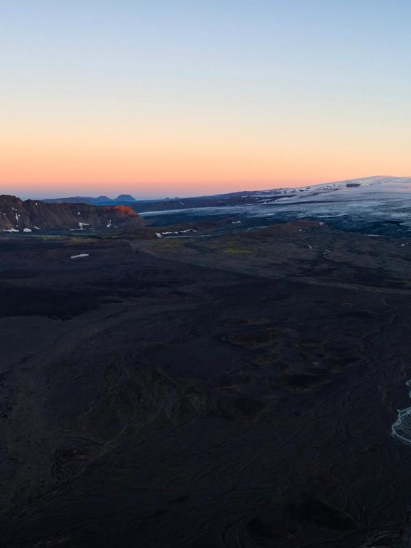 an aerial view of a mountain range with a river running through it at sunset .