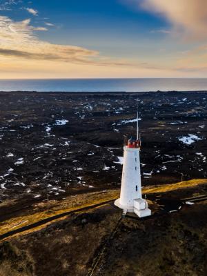 an aerial view of a lighthouse on top of a hill near the ocean .