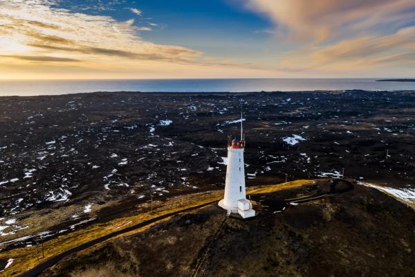A white and red lighthouse next to the sea