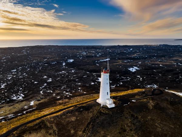an aerial view of a lighthouse on top of a hill near the ocean .