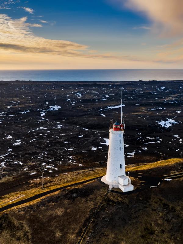 an aerial view of a lighthouse on top of a hill near the ocean .
