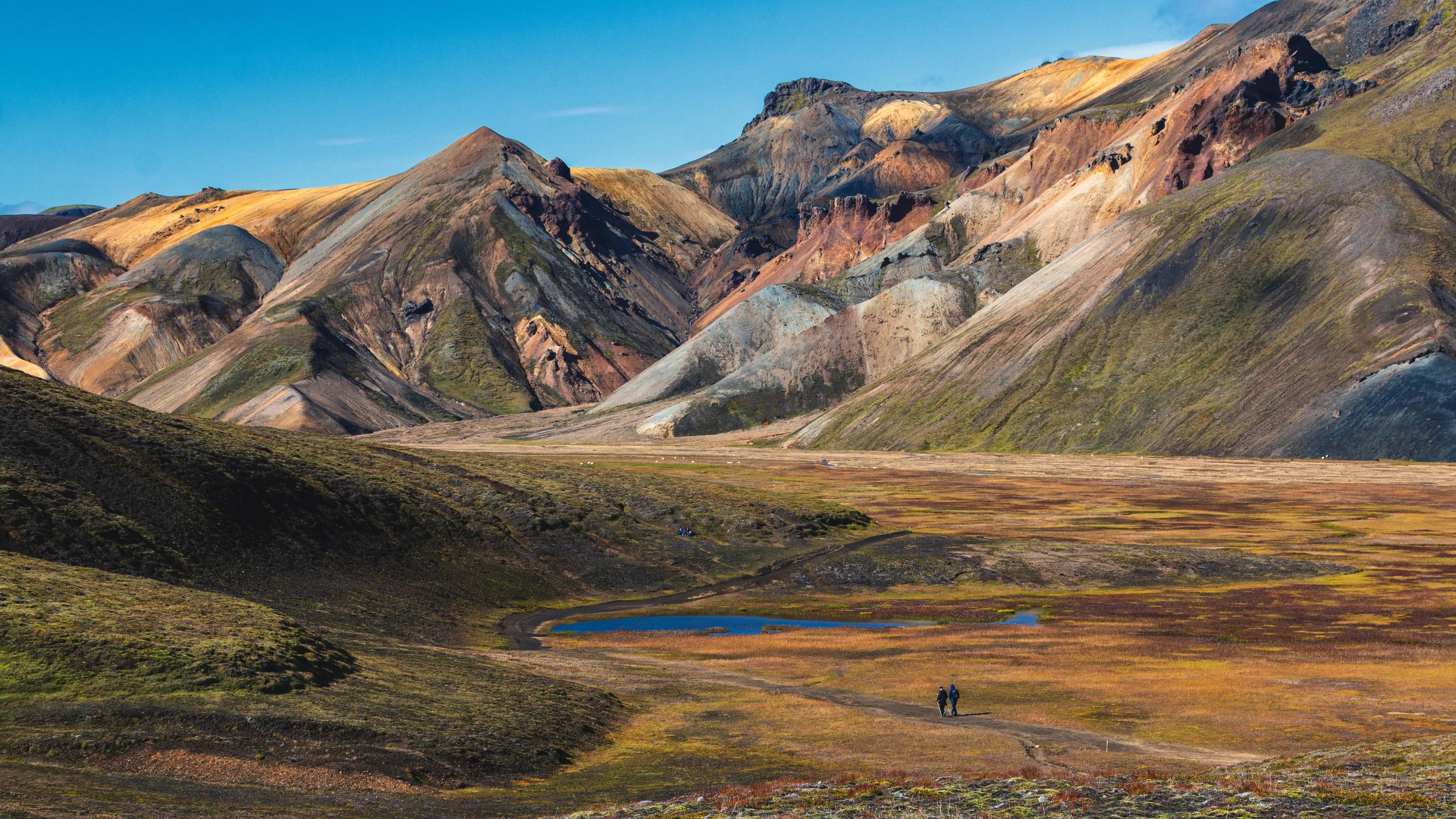 quelques personnes se promènent dans une vallée entourée de montagnes.