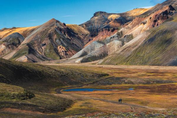 quelques personnes se promènent dans une vallée entourée de montagnes.