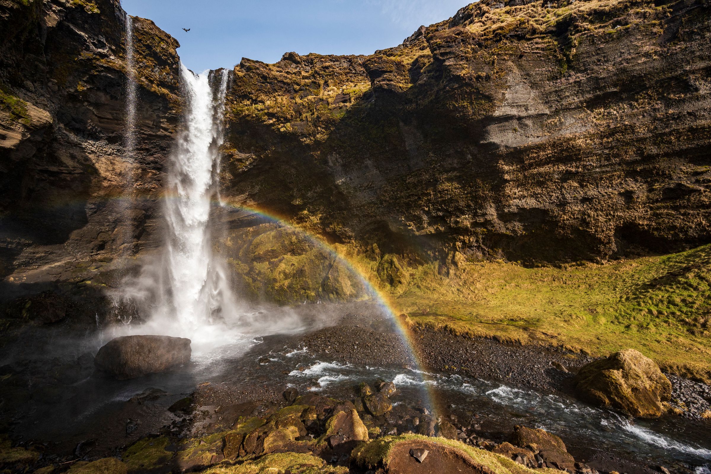 a waterfall with a rainbow in the middle of it at Kvernufoss in iceland.
