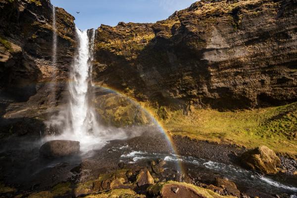 a waterfall with a rainbow in the middle of it at Kvernufoss in iceland.
