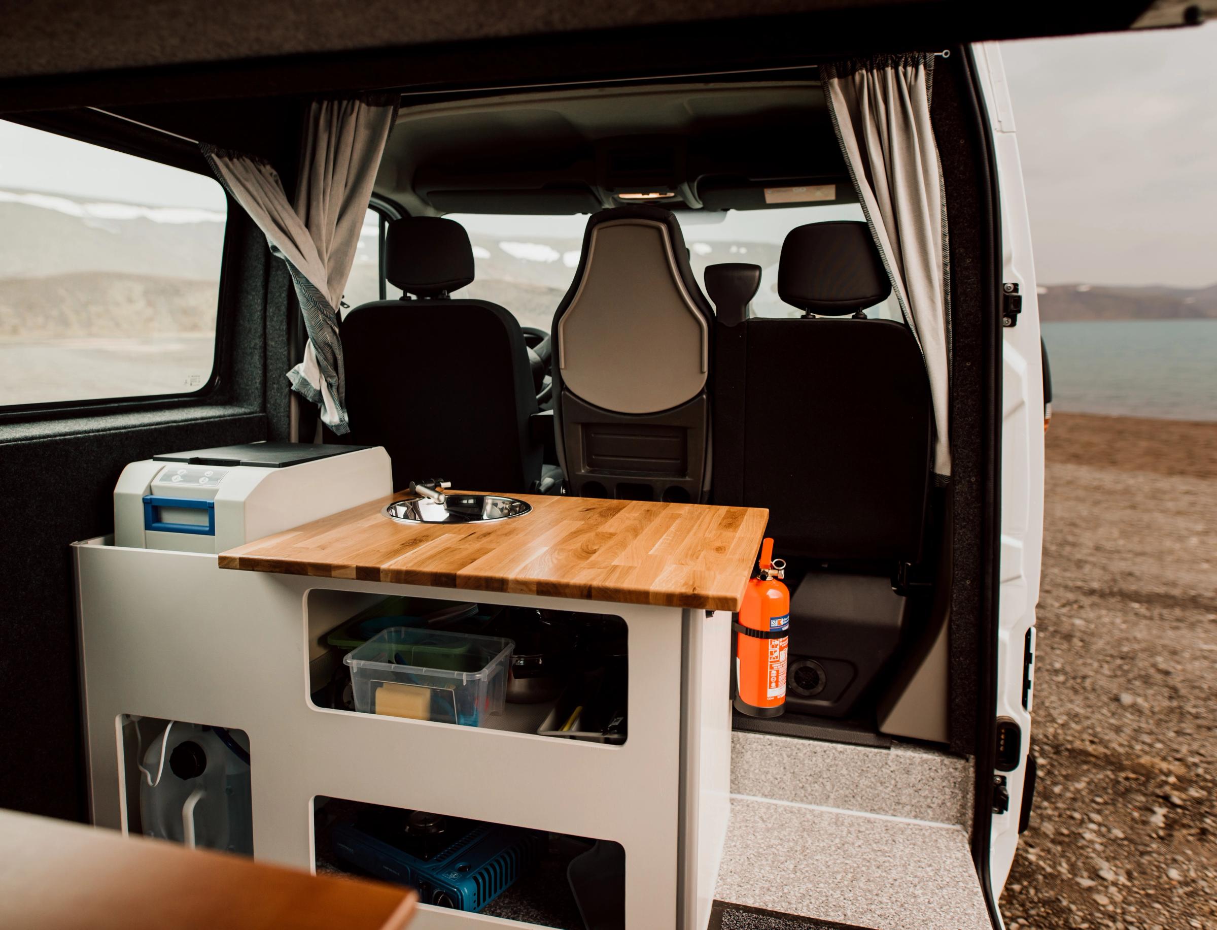 Küche mit Spüle, Holzarbeitsplatte, Kühlbox und Stauraum in einem geräumigen, preisgünstigen Camper für 5 Personen