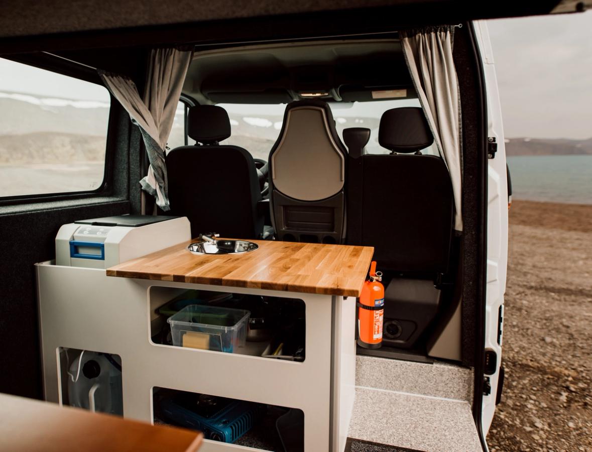 Küche mit Spüle, Holzarbeitsplatte, Kühlbox und Stauraum in einem geräumigen, preisgünstigen Camper für 5 Personen