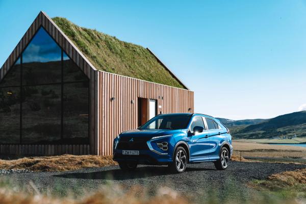 Mitsubishi Eclipse rental car A parked white Mitsubishi Eclipse Cross rental car with a house in the background