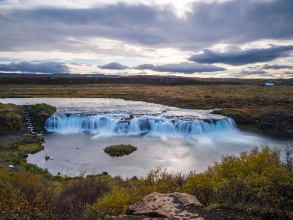 there is a waterfall in the middle of a river in the middle of a field .