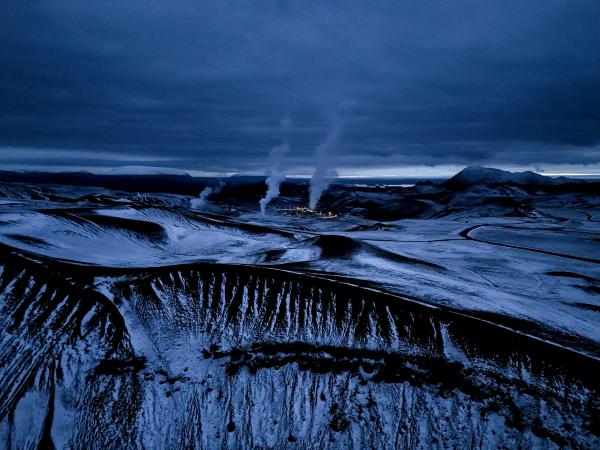 an aerial view of a volcano with steam coming out of it .