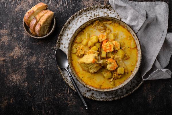 a bowl of soup with bread and a spoon on a plate .