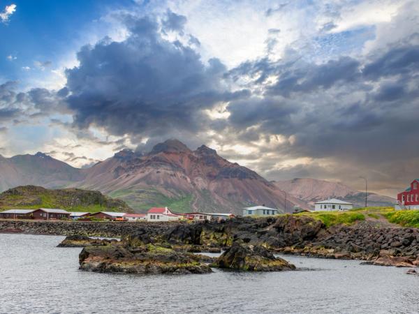 un pequeño pueblo a orillas de un lago con montañas de fondo .