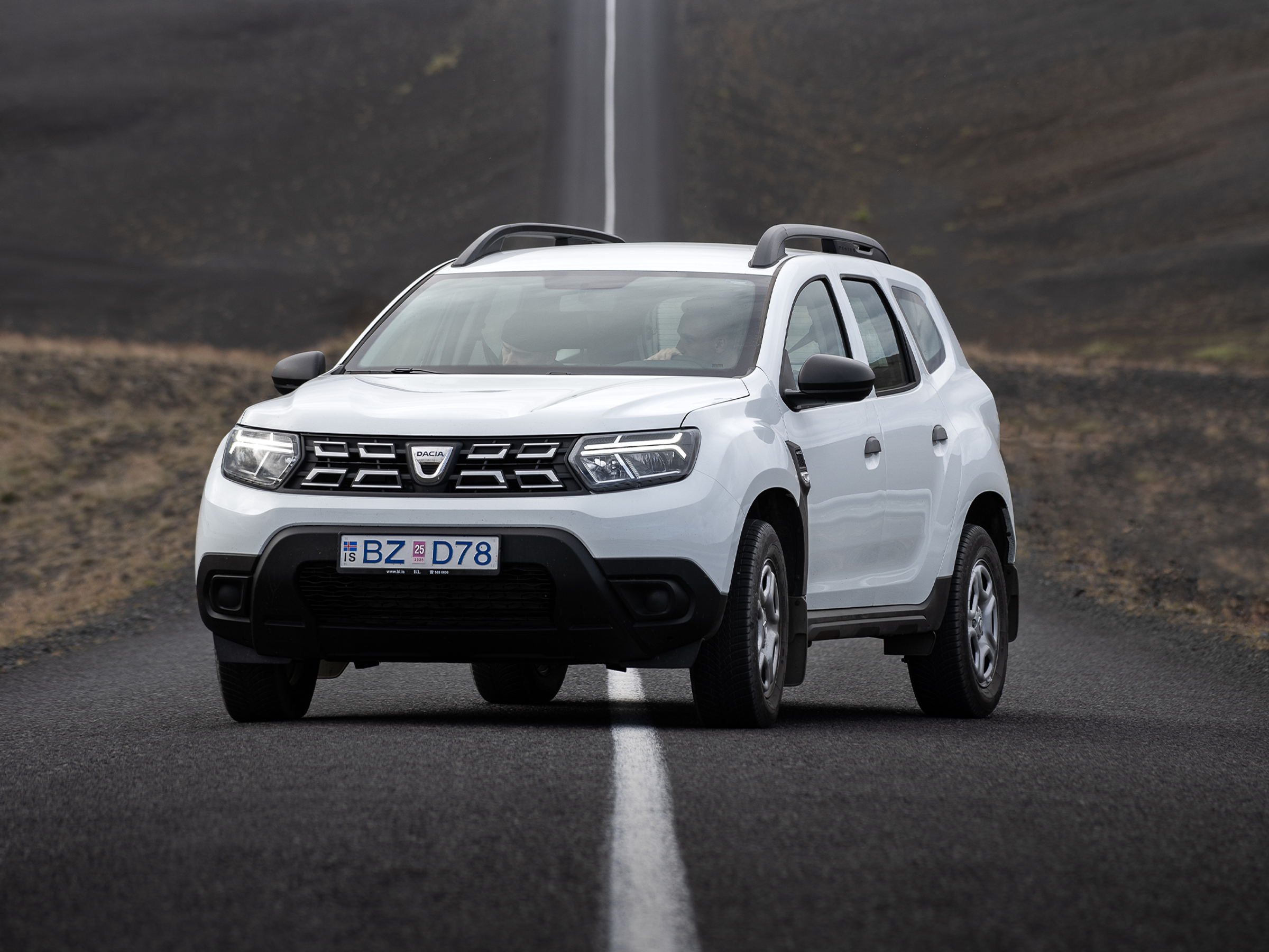White Dacia Duster SUV on a road in a barren landscape.