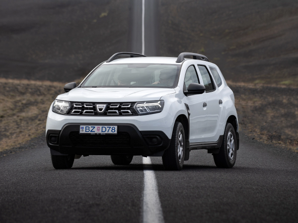 White Dacia Duster SUV on a road in a barren landscape.