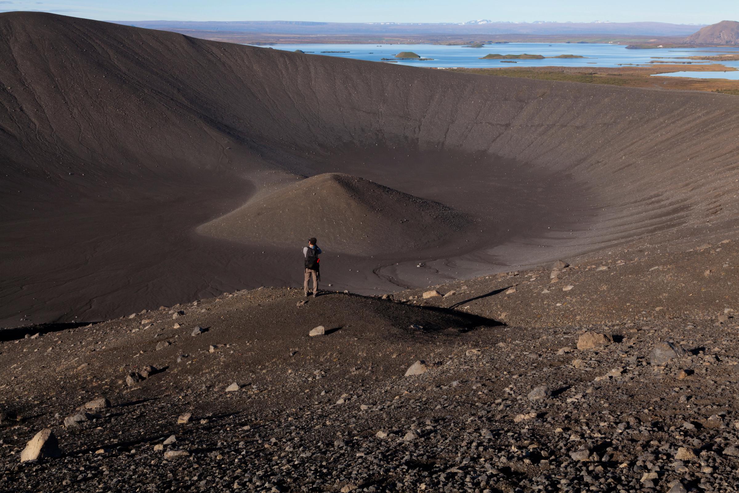 un hombre de pie en la cima de una colina rocosa con vista a un lago
