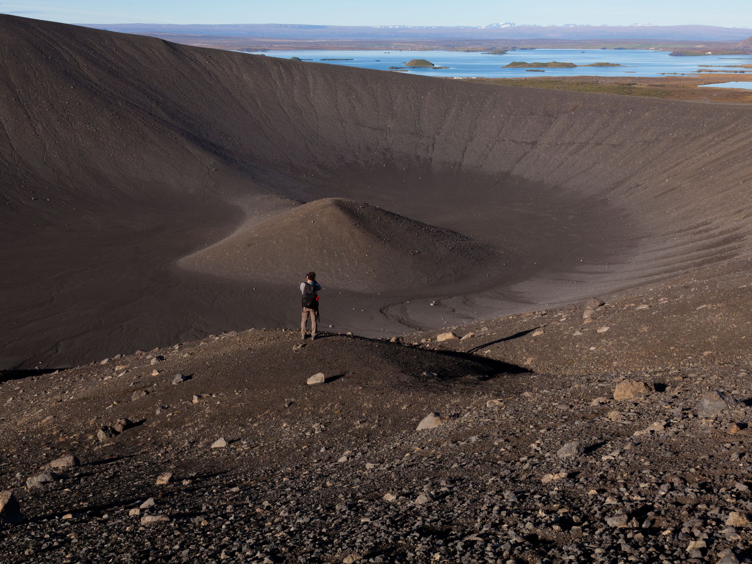 un hombre de pie en la cima de una colina rocosa con vista a un lago