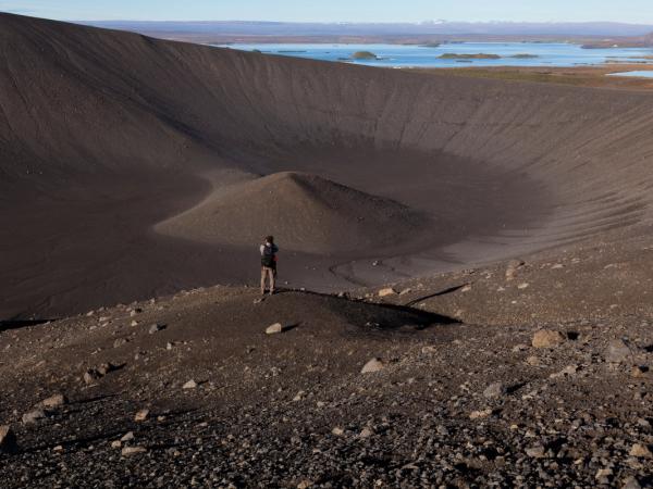 a man standing on top of a rocky hill overlooking a lake