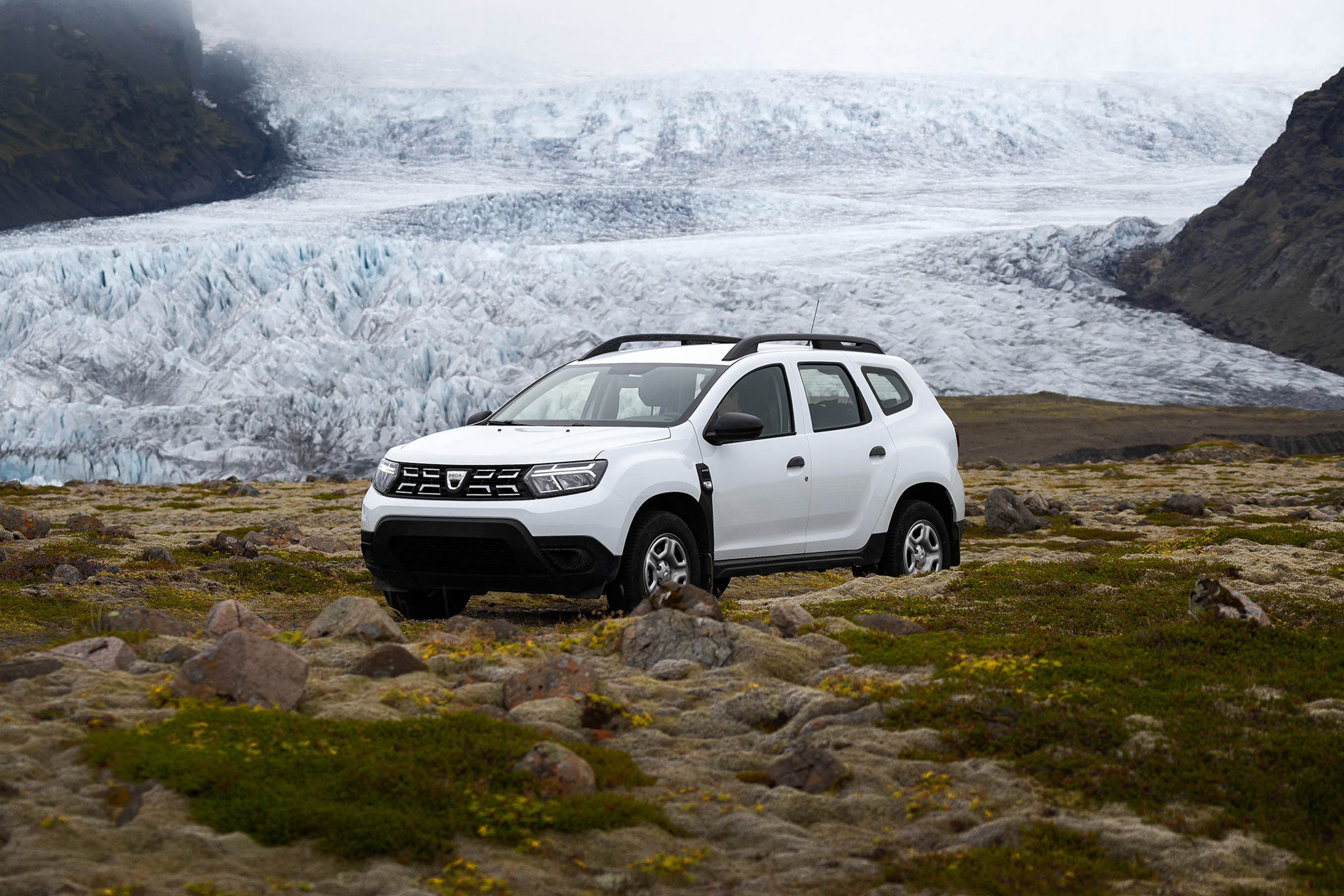 un duster blanco está aparcado frente a un glaciar