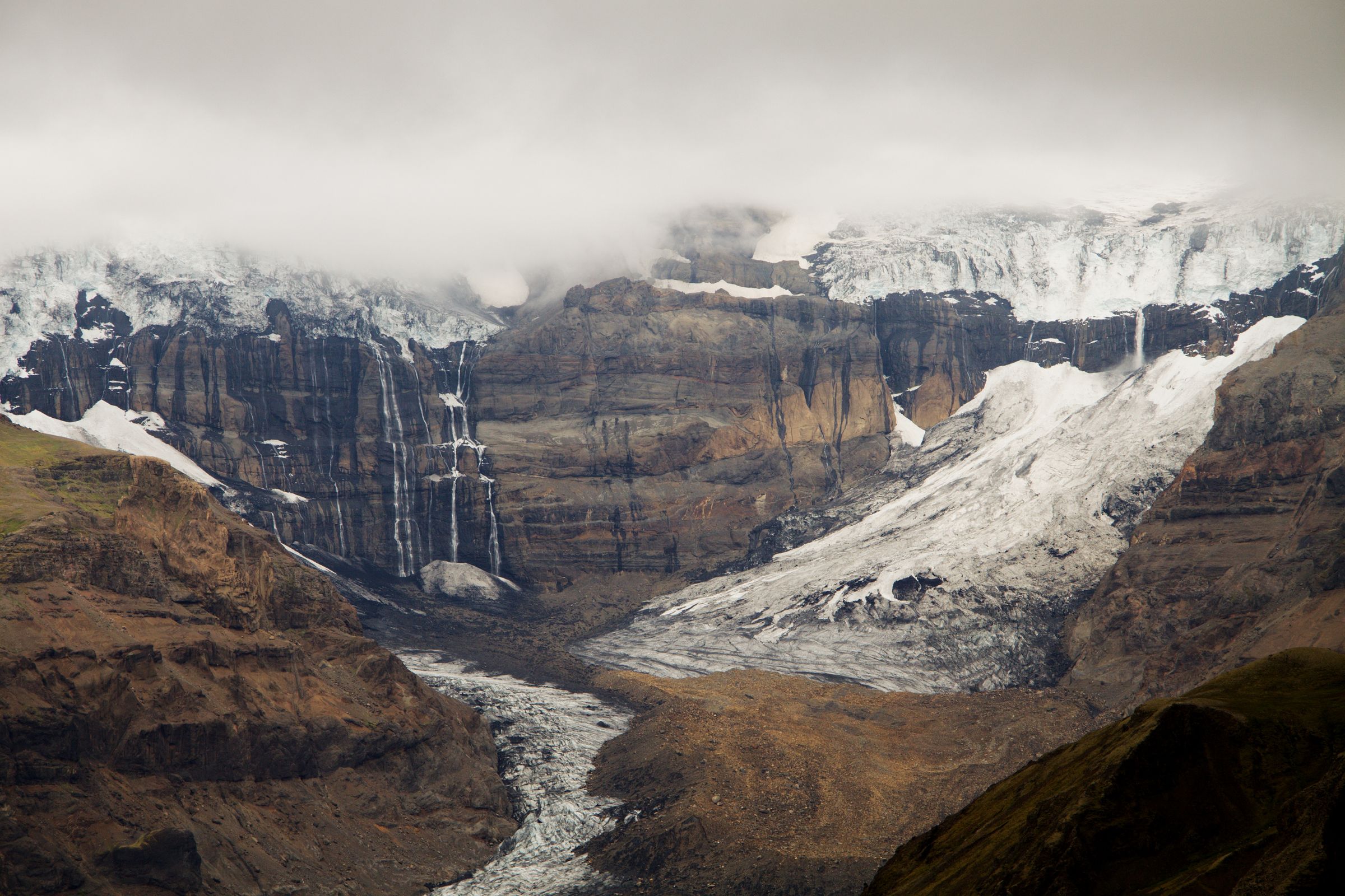 a mountain covered in snow and ice with a river running through it at Morsárjökull in skaftafell, iceland.