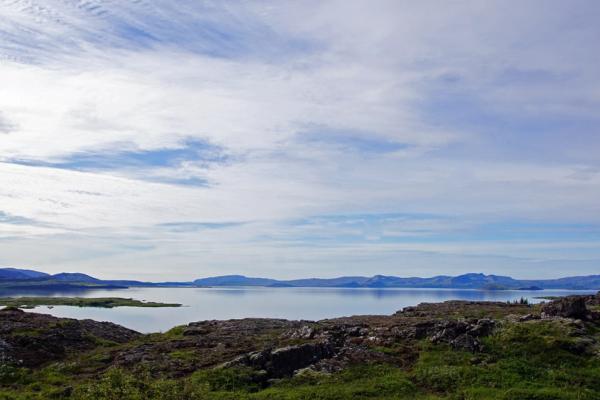 a large body of water surrounded by mountains on a cloudy day .