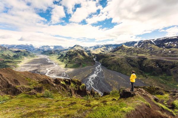 Hiker standing seeing river flowing through in icelandic highlands at Thórsmörk