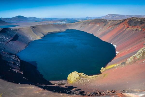 a large blue lake is surrounded by red rocks and mountains, Ljótipollur Crater Lake