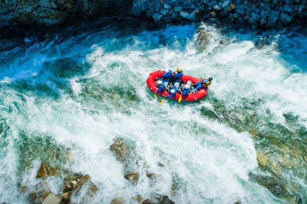 a group of people are rafting down a river .