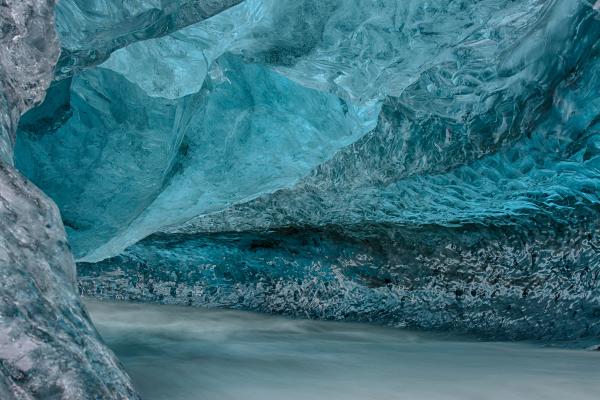 Blue ice cave interior with a flowing stream.