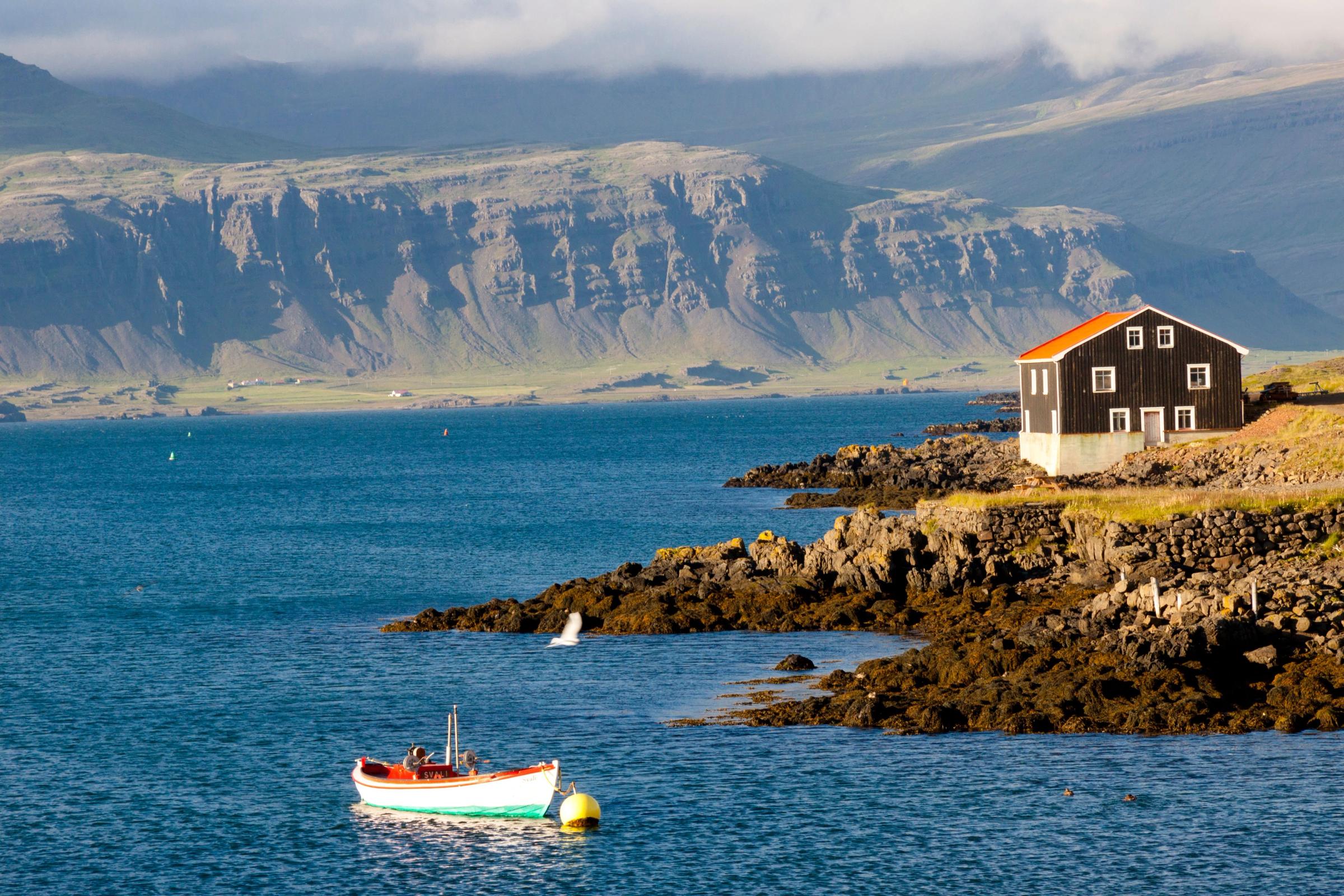 House on a cliff and a boat on the sea, Djúpivogur, Iceland