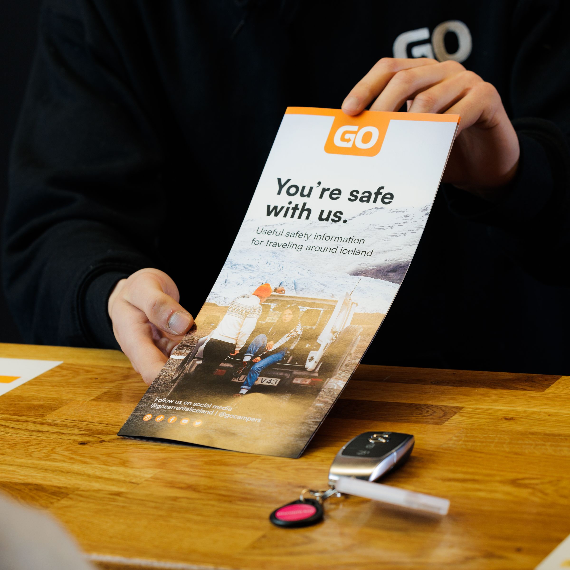 a man is holding a brochure in front of a woman at a table .