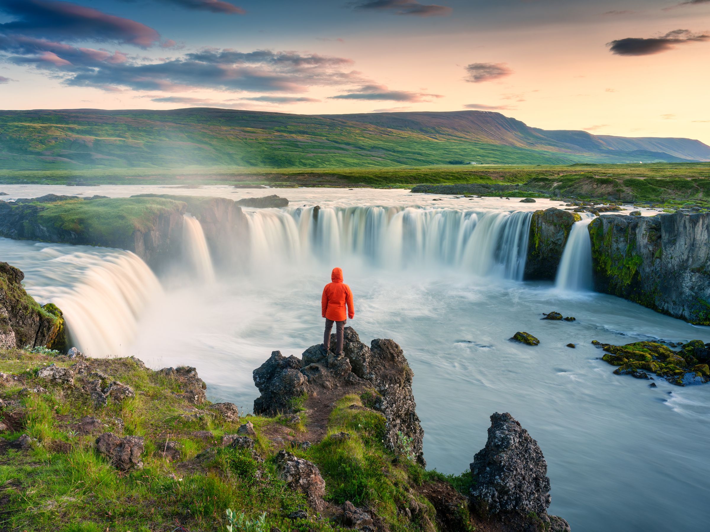 Personne portant un imperméable rouge devant une chute d'eau
