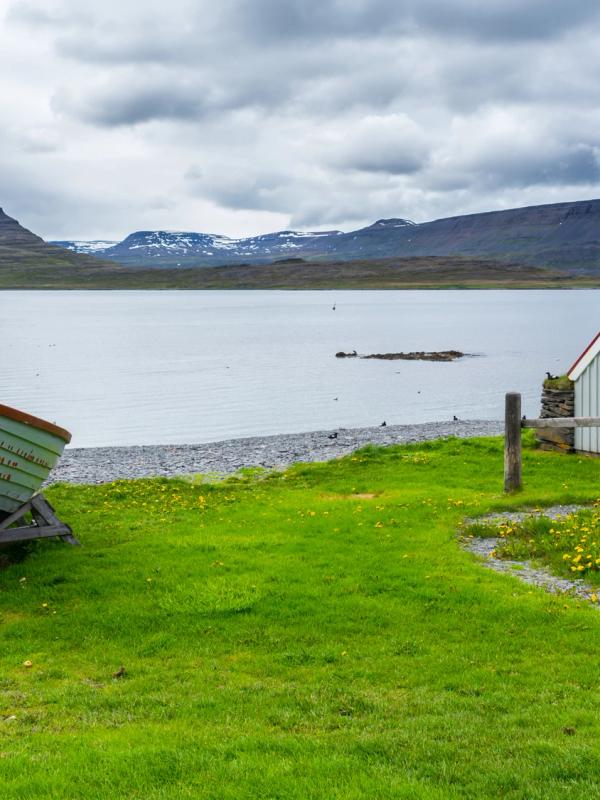 there is a boat and a house on the shore of a lake .
