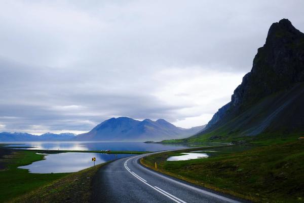 una carretera que atraviesa una zona montañosa con un lago y montañas al fondo.