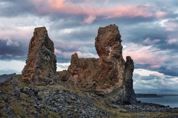 a group of rocks sitting on top of a hill next to a body of water .