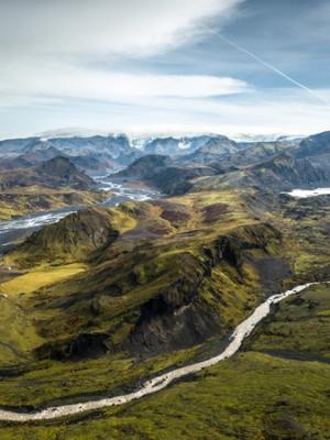 an aerial view of a river running through a valley surrounded by mountains, Thórsmörk