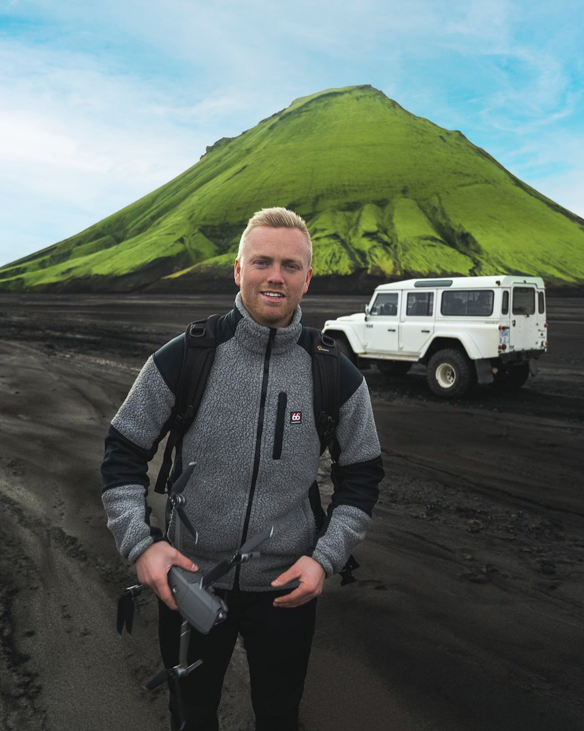 a man holding a drone in front of a mountain