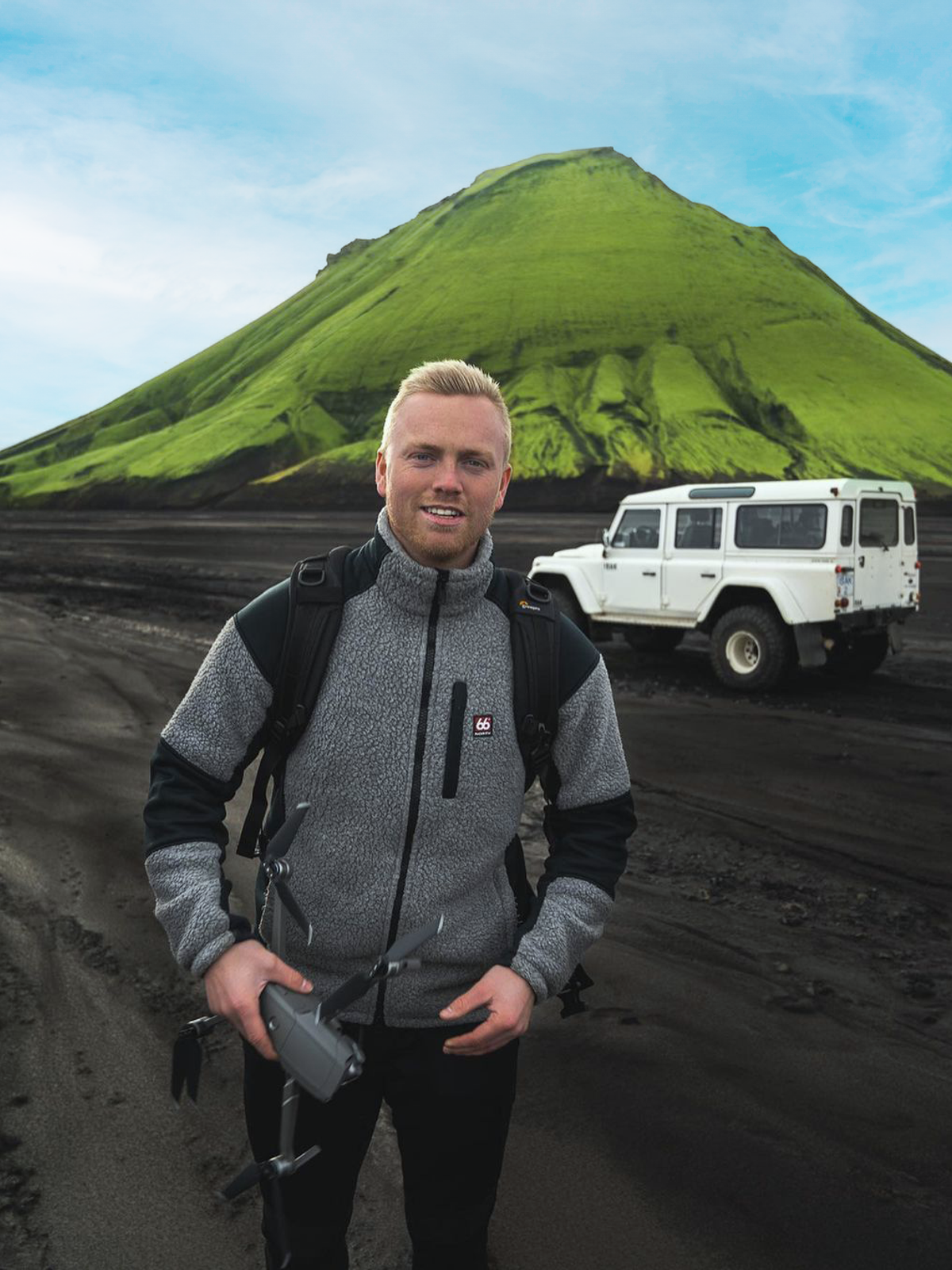a man holding a drone in front of a mountain