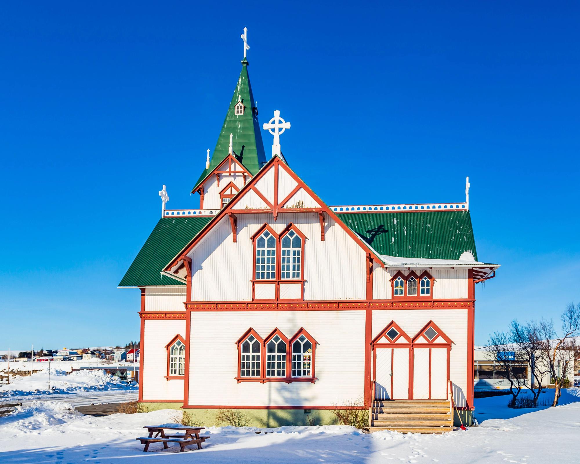 una iglesia blanca con un techo verde y una cruz en la cima.