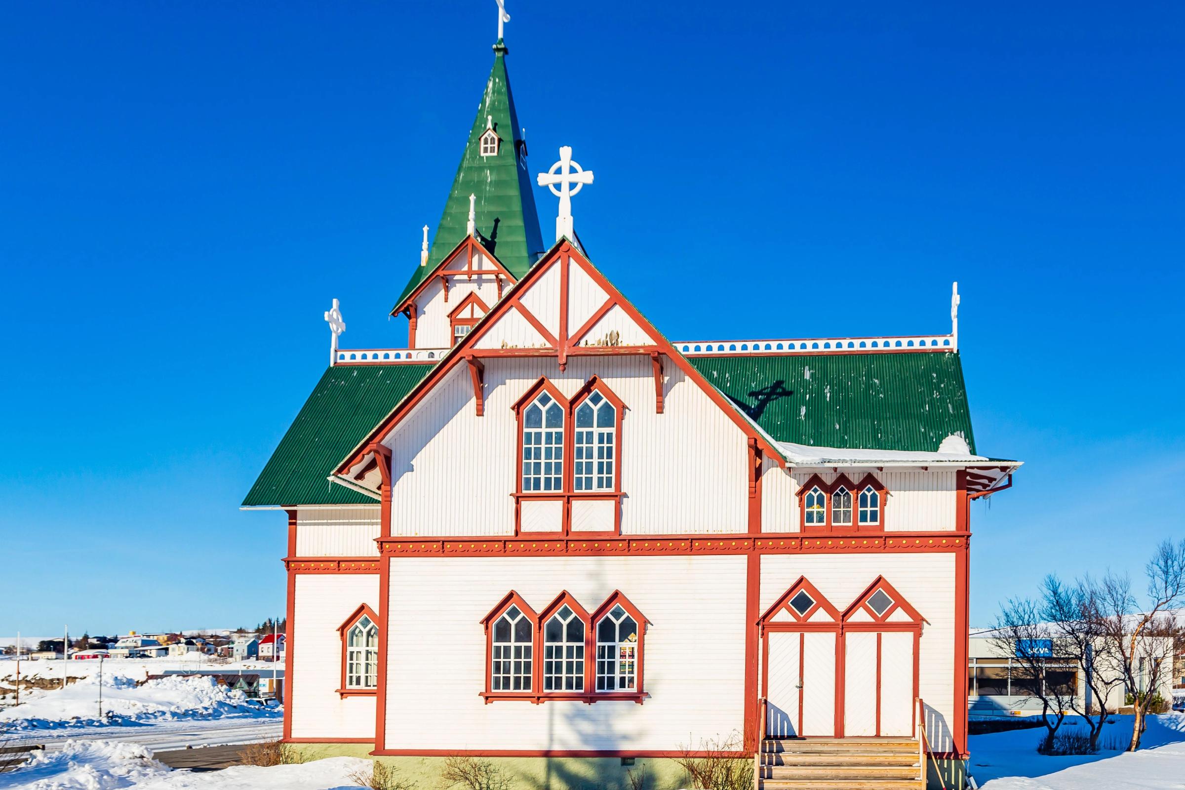una iglesia blanca con un techo verde y una cruz en la cima.