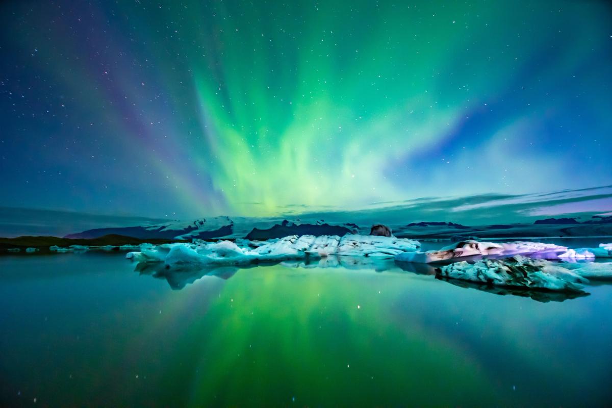 the aurora borealis is reflected in the water of a lake .